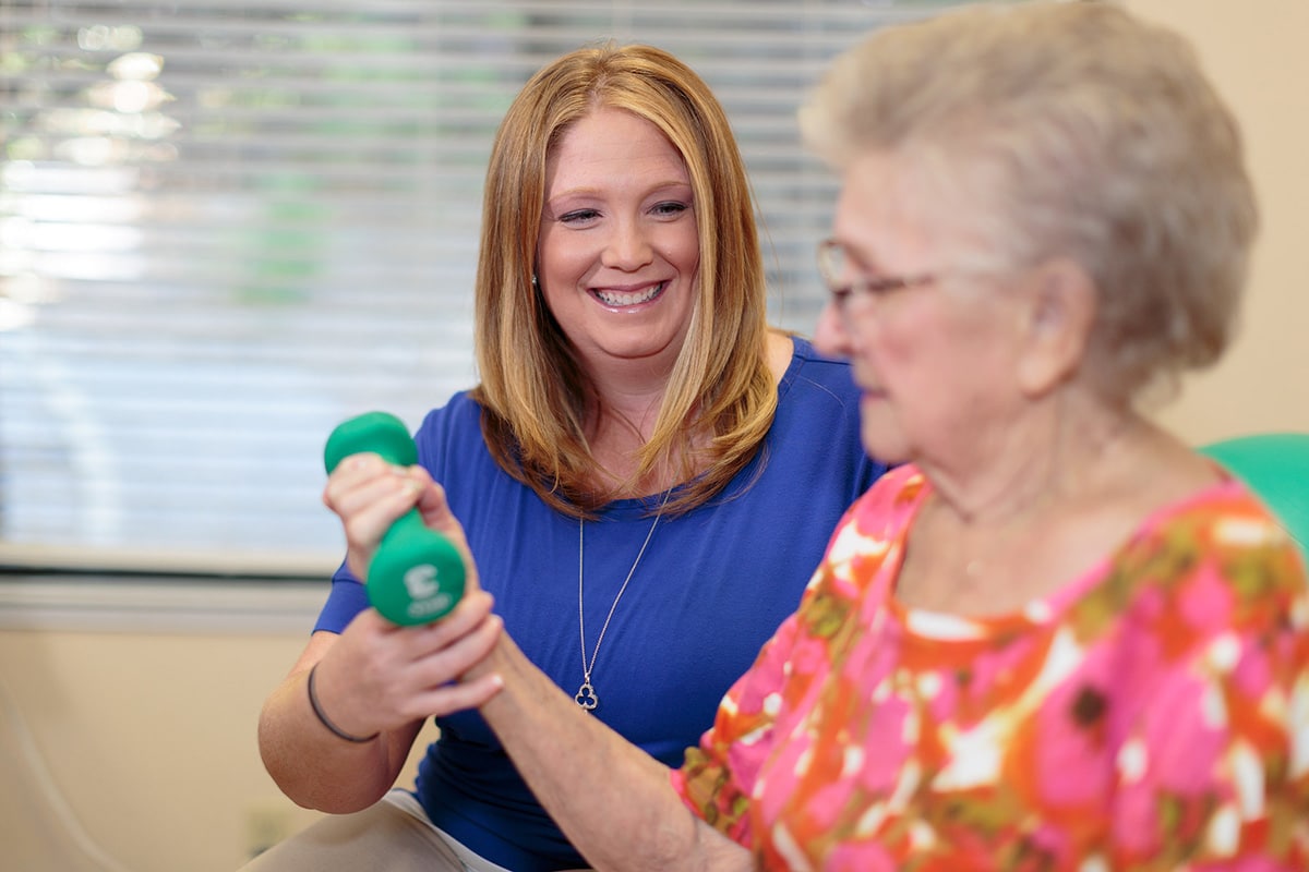 Female therapist helping a female elderly with arm exercises