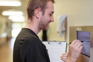Male therapist interacting with a tablet attached to a wall