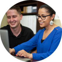 Professional woman in a bright blue top and black frame glasses typing on a computer
