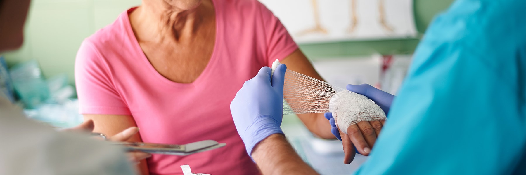 A nurse applying a gauss wrap to an elderly patient's hand.
